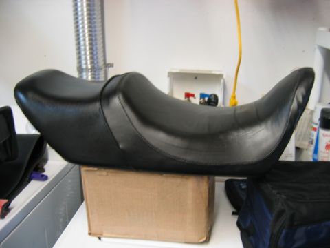 1985 Ford LTD Crown Victoria - This black motorcycle seat is presented on a cardboard box, with various items in the background.