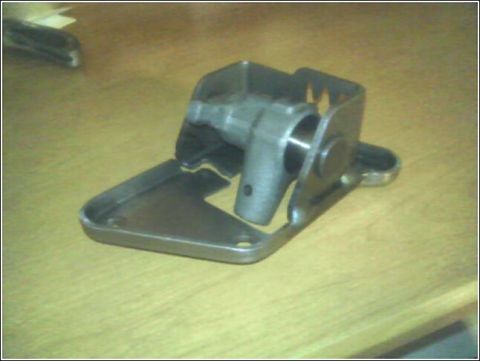 1989 Mazda MX-6 - A close-up view of a metal component, likely from a vehicle, rests on a wooden table.