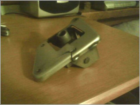 1989 Mazda MX-6 - A metal bracket with a pivot mechanism is shown on a wooden surface.