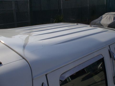 1993 Ford C-350 (Centurion Conversions) - The ribbed roof of a white van is visible, with a covered vehicle in the background.