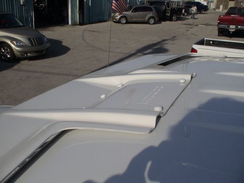 1993 Ford C-350 (Centurion Conversions) - A white roof fairing is shown mounted on a vehicle's roof, with other vehicles and a building in the background.