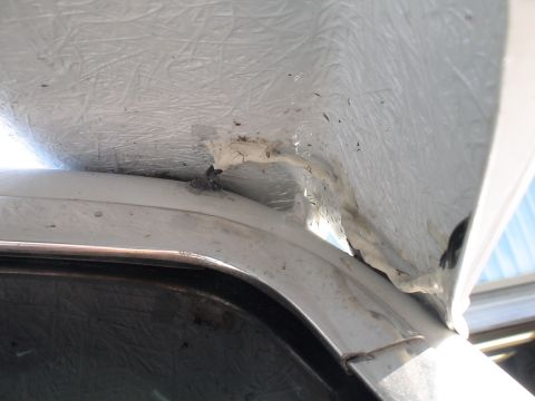 1993 Ford C-350 (Centurion Conversions) - Close-up of a fiberglass moonvisor attachment to a vehicle's roofline, showing sealant and trim details of the trim.