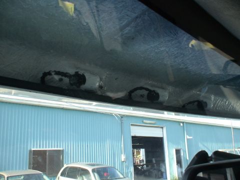 1993 Ford C-350 (Centurion Conversions) - View of the interior overhead console with lights and a yellow sticker, with a blue building and other vehicles visible outside.