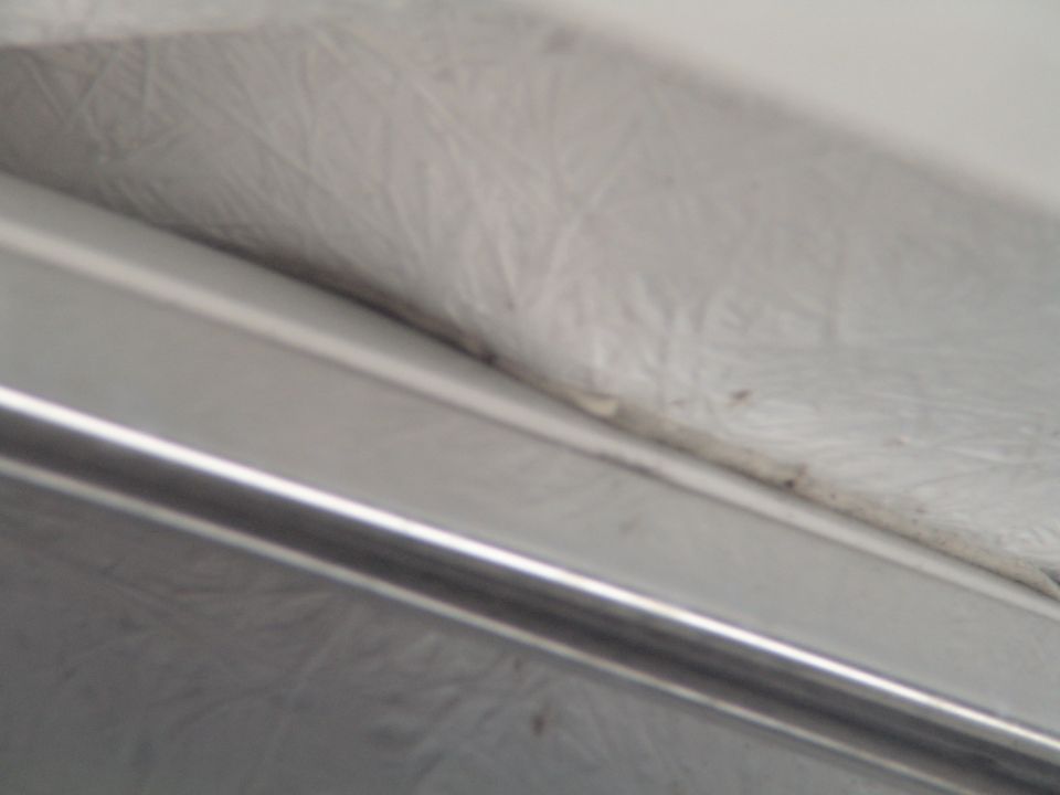Close-up of textured white upholstery and a metal trim piece inside a vehicle