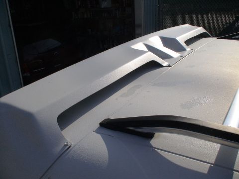 1993 Ford C-350 (Centurion Conversions) - Close-up of a white rear spoiler with a textured finish and angular design elements.
