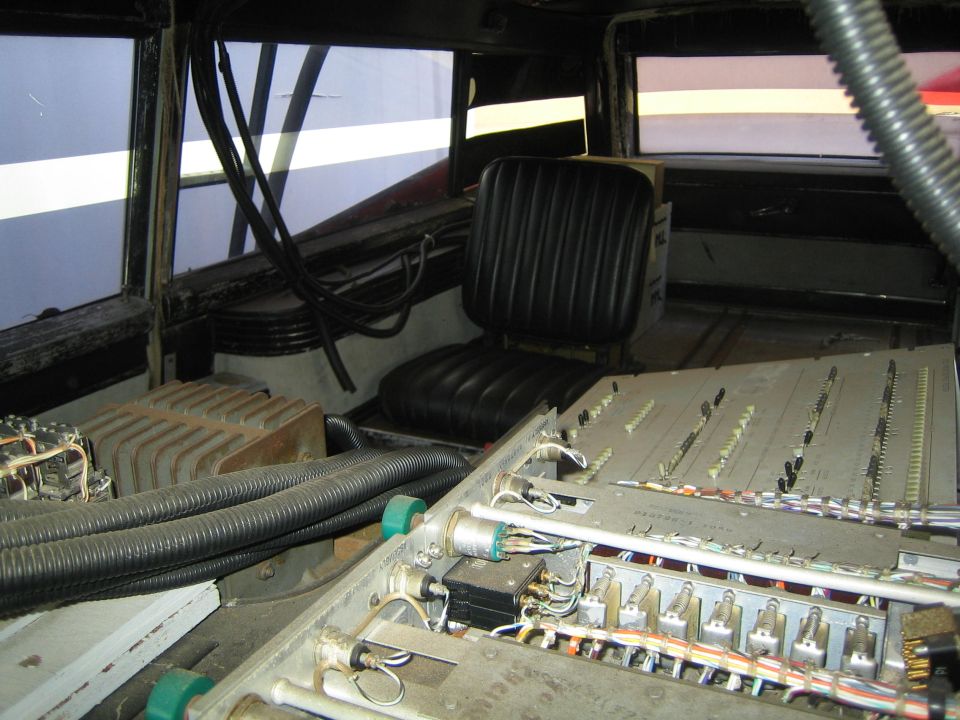Interior rear of a vehicle packed with wiring, hoses and a black seat