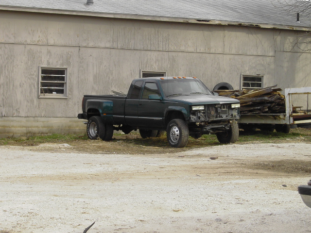 1995 GMC C/K Pickup dually truck parked in front of a building, missing grille and headlights