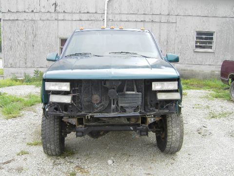 1995 GMC C/K Pickup - Front view of a green 1995 GMC C/K Pickup truck, showing its missing grille and bumper assembly.