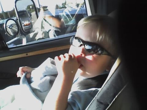 1993 Ford C-350 (Centurion Conversions) - A child with sunglasses looks out the window of a vehicle, with another car reflected in the side mirror.