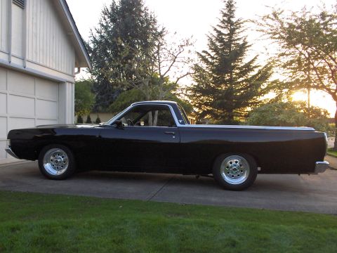 1968 Ford Ranchero - A side view of a black pickup truck with a white trim, parked in a driveway during sunset.