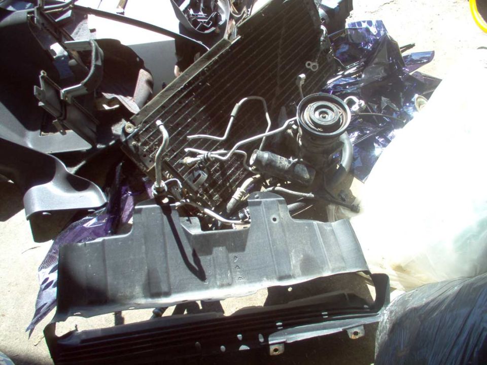 Disassembled car radiator, hoses and black plastic panel parts on concrete