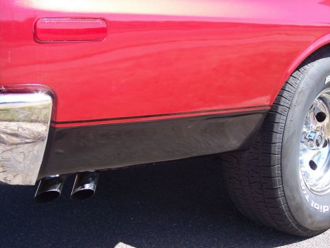 1972 Ford Ranchero - Close-up of a 1972 Ford Ranchero's rear quarter panel showing its red paint and dual exhaust.