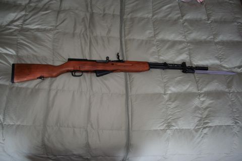 2004 Jeep TJ - A rifle with a wooden stock and a bayonet is displayed on a quilted surface.