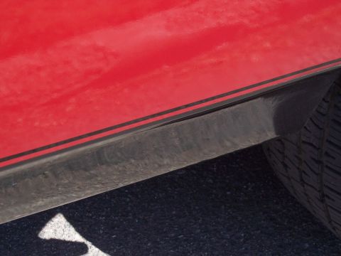 1972 Ford Ranchero - Close-up of a 1972 Ford Ranchero's red quarter panel a black stripe and part of the tire.