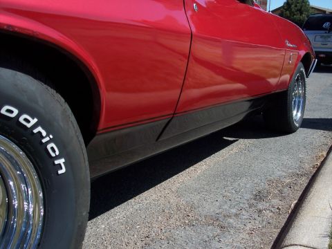 1972 Ford Ranchero - Close-up of a red car's side panel and tire, with a black stripe accent.