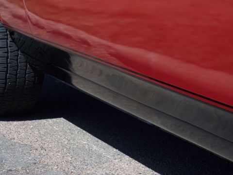 1972 Ford Ranchero - Close-up of a red vehicle's side panel, showing black trim and a portion of the tire.