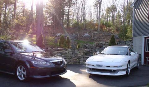 1996 Ford Probe - Two cars, a white 1996 Ford Probe GT and a dark Mazda 6, are parked in a driveway next to a garage.
