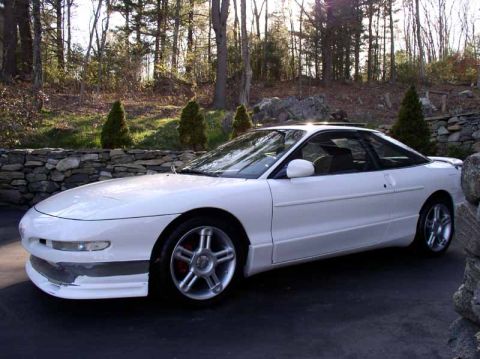 1996 Ford Probe - A white 1996 Ford Probe GT is parked in front of a stone wall and trees.