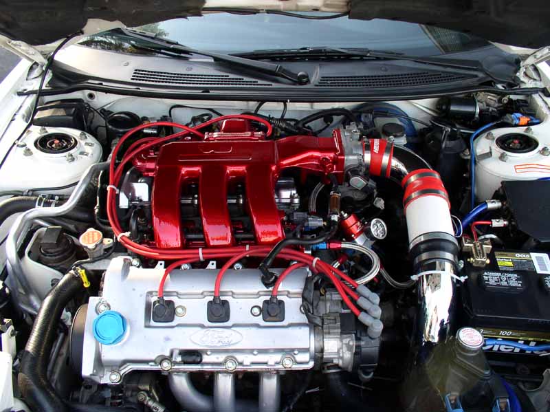 Engine bay with shiny red intake manifold and Ford branding on silver engine block