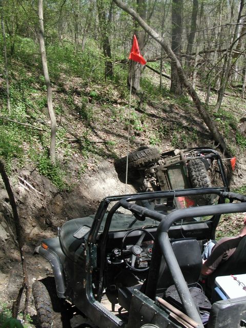 1992 Ford Bronco - Off-road vehicles navigate a challenging wooded trail, with one vehicle overturned.