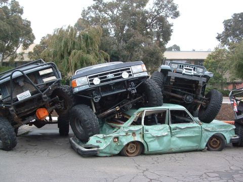 1994 Jeep YJ - Several modified off-road vehicles are stacked on top of a severely damaged sedan.
