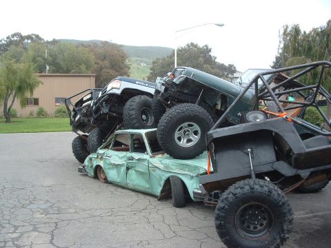 1994 Jeep YJ - Several modified off-road vehicles are piled on top of a heavily damaged sedan.