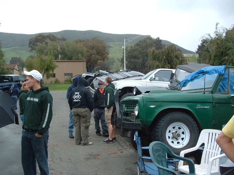 Green Bronco with a blue tarp over the windshield, parked outdoors