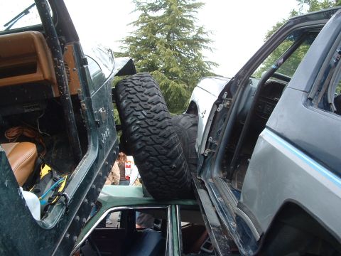 1994 Jeep YJ - Two off-road vehicles are entangled, with a large spare tire lodged between their open doors.