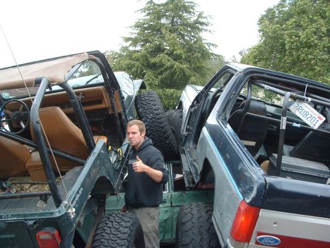 1994 Jeep YJ - Two Jeep YJs are parked side-by-side, with a man standing between them. The green Jeep is on the left, and the dark blue one is on the righ…
