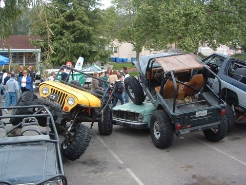 1994 Jeep YJ - Several off-road vehicles are piled on top of each other in a parking lot, with spectators around.