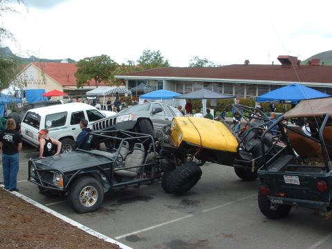 1994 Jeep YJ - Multiple custom off-road vehicles are gathered at an event, including a buggy with a prominent yellow hood.