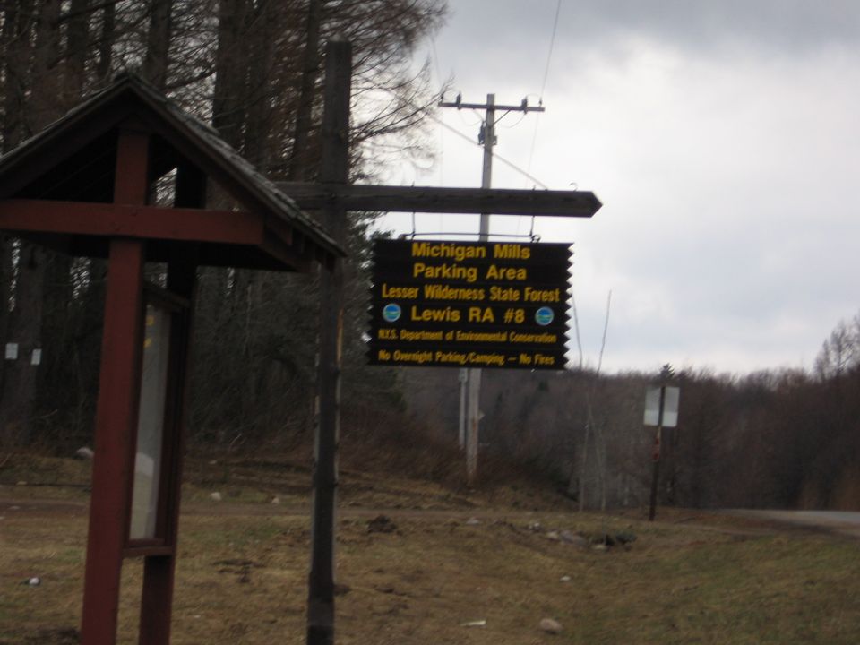 Michigan Mills Parking Area sign for Lesser Wilderness State Forest on an overcast day