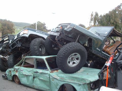 1994 Jeep YJ - Multiple off-road vehicles are piled on top of a wrecked sedan, creating a chaotic scene.