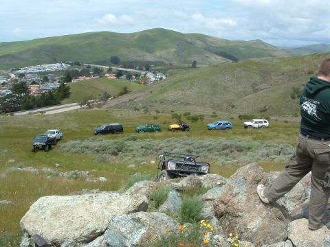 1994 Jeep YJ - A group of off-road vehicles navigate a scenic, hilly terrain, with a town visible in the distance.