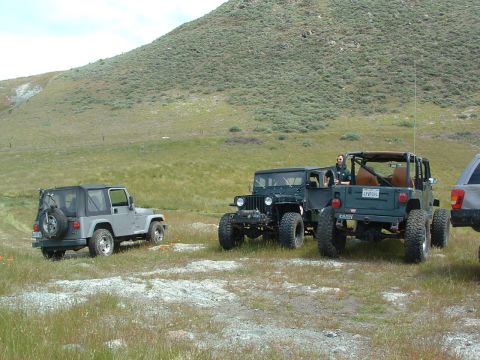 1994 Jeep YJ - Several Jeeps are parked in a grassy area with a large hill in the background.