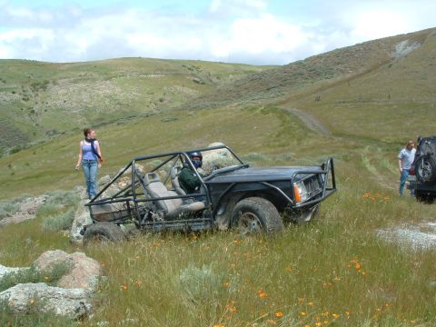 1994 Jeep YJ - Modified Jeep Cherokee XJ-based off-road vehicle navigates a grassy, hilly terrain.