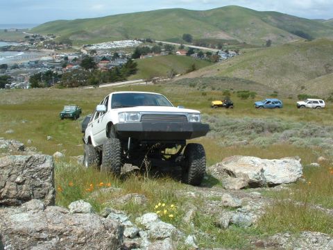 1994 Jeep YJ - Modified Toyota pickup truck navigating off-road terrain with other vehicles in the distance.