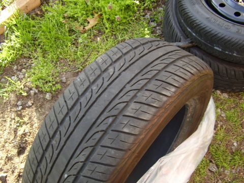 1997 Ford Taurus - A car tire is shown in close-up, resting on grass next to another tire.