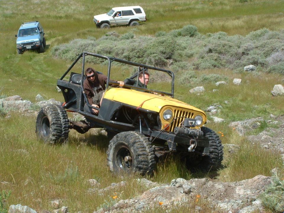 Yellow custom buggy with roll cage and large tires, driven off-road with two people inside