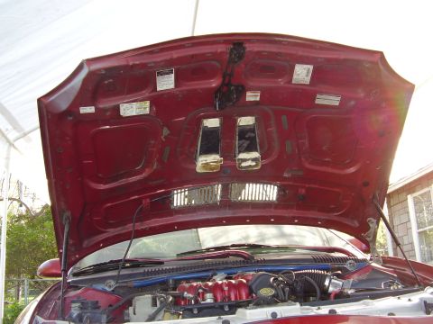 1997 Ford Taurus - The underside of a car's hood is open, revealing the engine compartment and various labels.