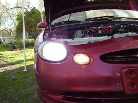 1997 Ford Taurus - The front of a red 1997 Ford Taurus is shown with its hood open, revealing the engine compartment.