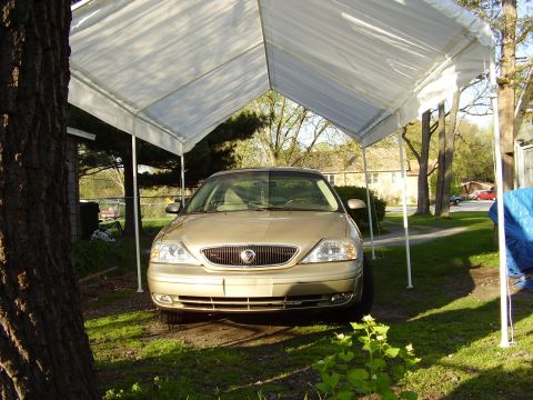 1997 Ford Taurus - A gold Mercury Sable is parked under a white canopy on a sunny day.