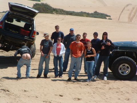 1994 Jeep YJ - A group gathers for a photo with two off-road vehicles in a sandy landscape, with one person humorously posing.