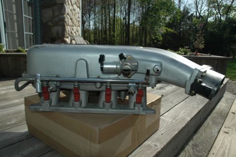 2000 Ford Mustang - This is an intake manifold with fuel injectors, likely for a car engine, placed outdoors on a deck.