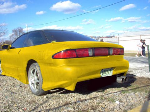 1994 Ford Probe - A bright yellow 1994 Ford Probe is seen from the rear, a black roof and custom dual exhaust pipes.