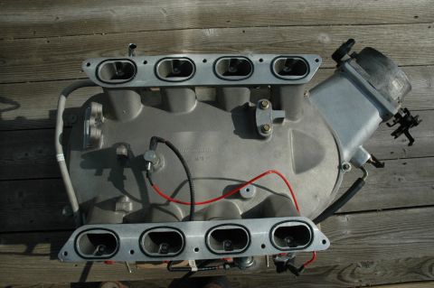2000 Ford Mustang - An intake manifold, likely from a Ford vehicle, is shown laid out on a wooden surface.