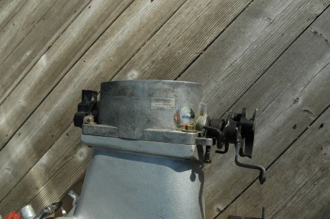 2000 Ford Mustang - A metal throttle body part is shown against a background of weathered wooden planks.