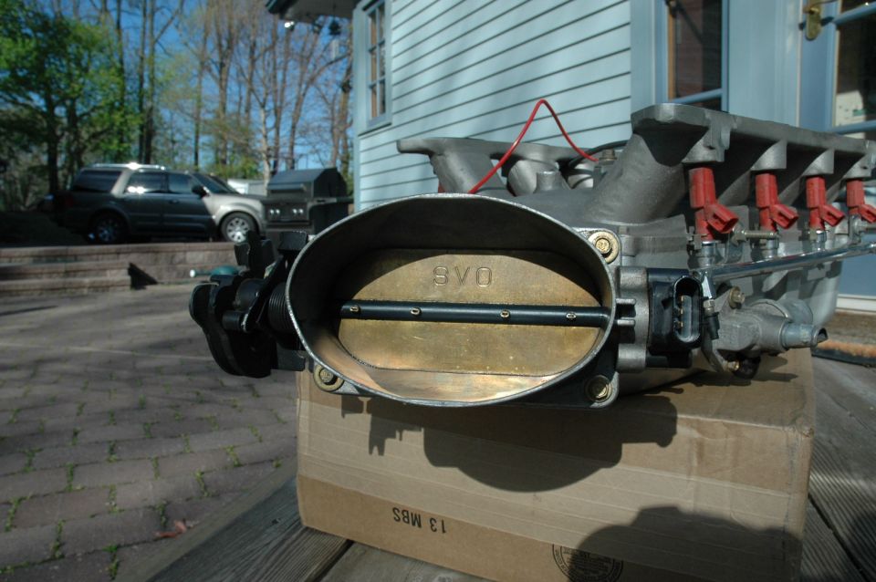 Ford Mustang intake manifold with SVO throttle body, sitting on a cardboard box outdoors