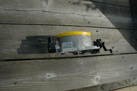 2000 Ford Mustang - A throttle body part, possibly for an older vehicle, is shown on a weathered wooden background.