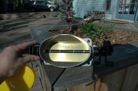 2000 Ford Mustang - Throttle body part with "COBRA R" engraving is held in hand outdoors.